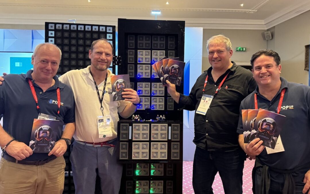 Four people standing in front of a lego z16 mainframe, smiling